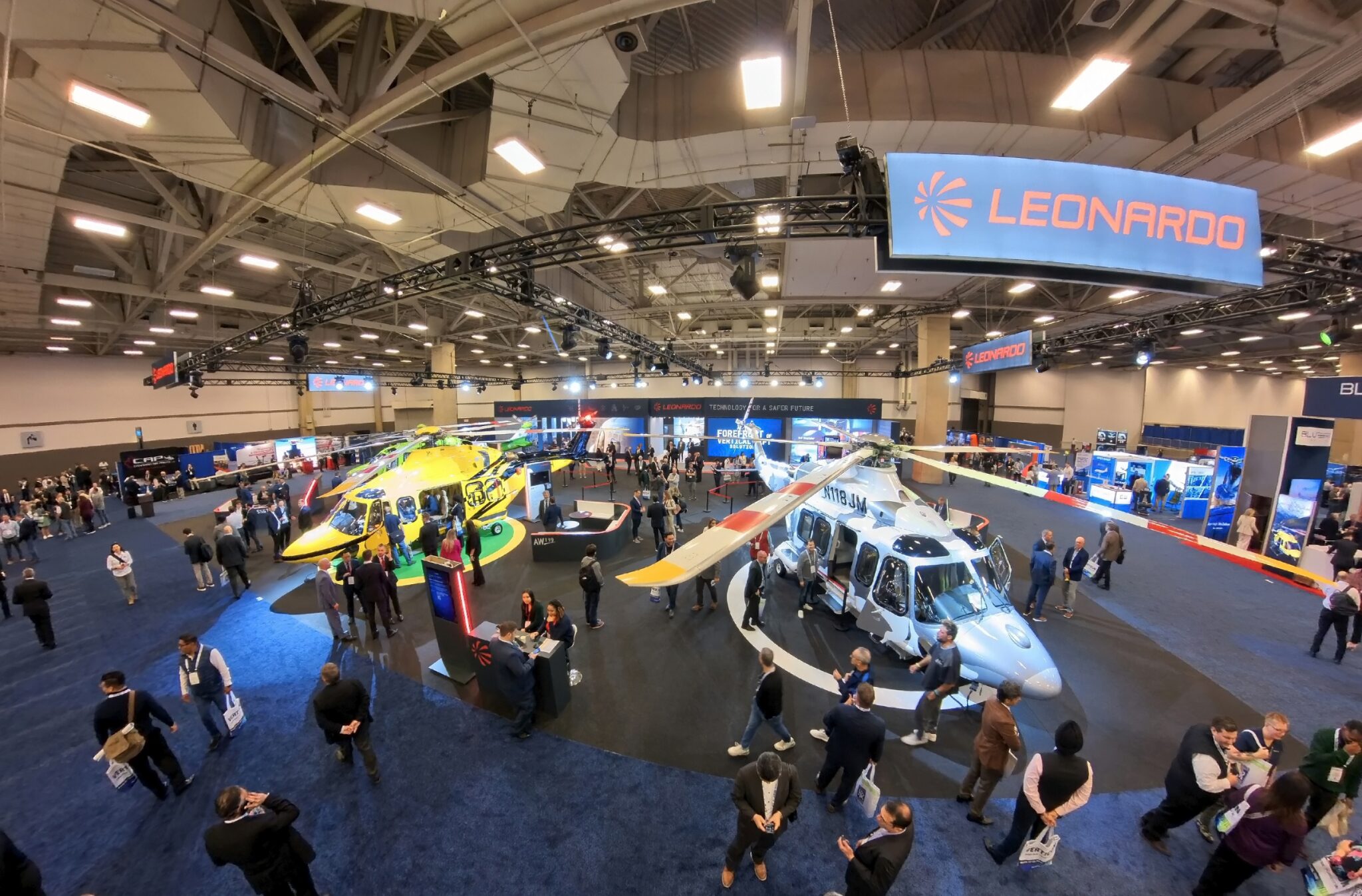 Leonardo, elicotteri, Verticon 2025. Esposizione industriale con stand, persone, vista dall'alto.